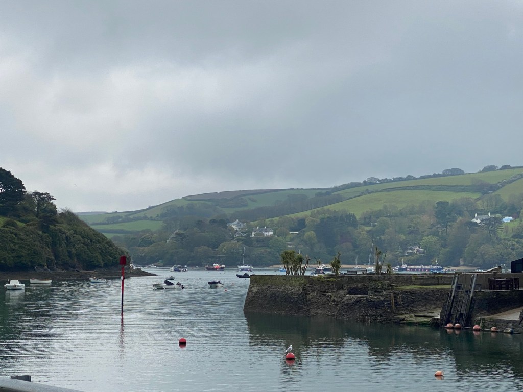 Image showing a quayside on a rainy day. There are green hills in the background and water and navigation marks in the foreground.